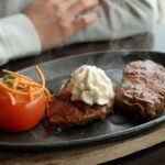 Seared bison steak topped with a melting porcini butter on a warm plate