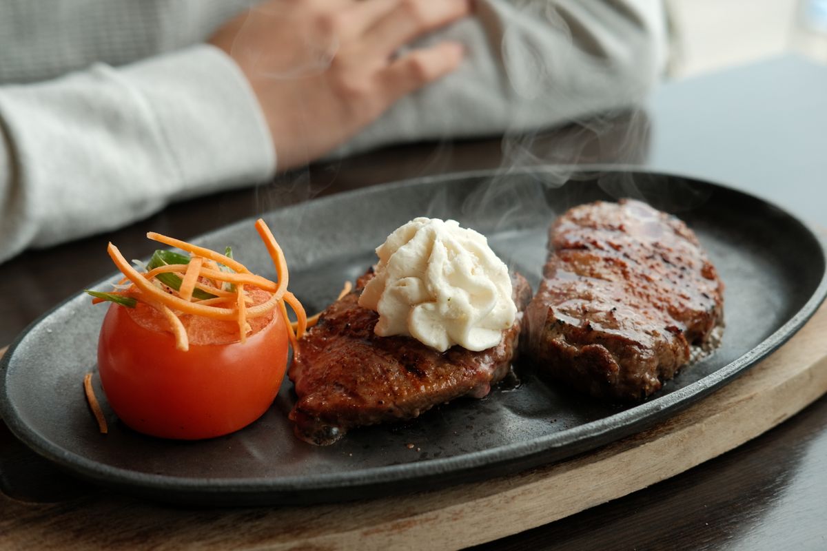 Seared bison steak topped with a melting porcini butter on a warm plate
