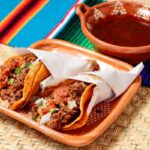 Goat birria tacos with a cup of consomme