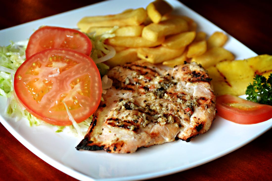 Grilled chicken breast plated with a fresh green salad and sides