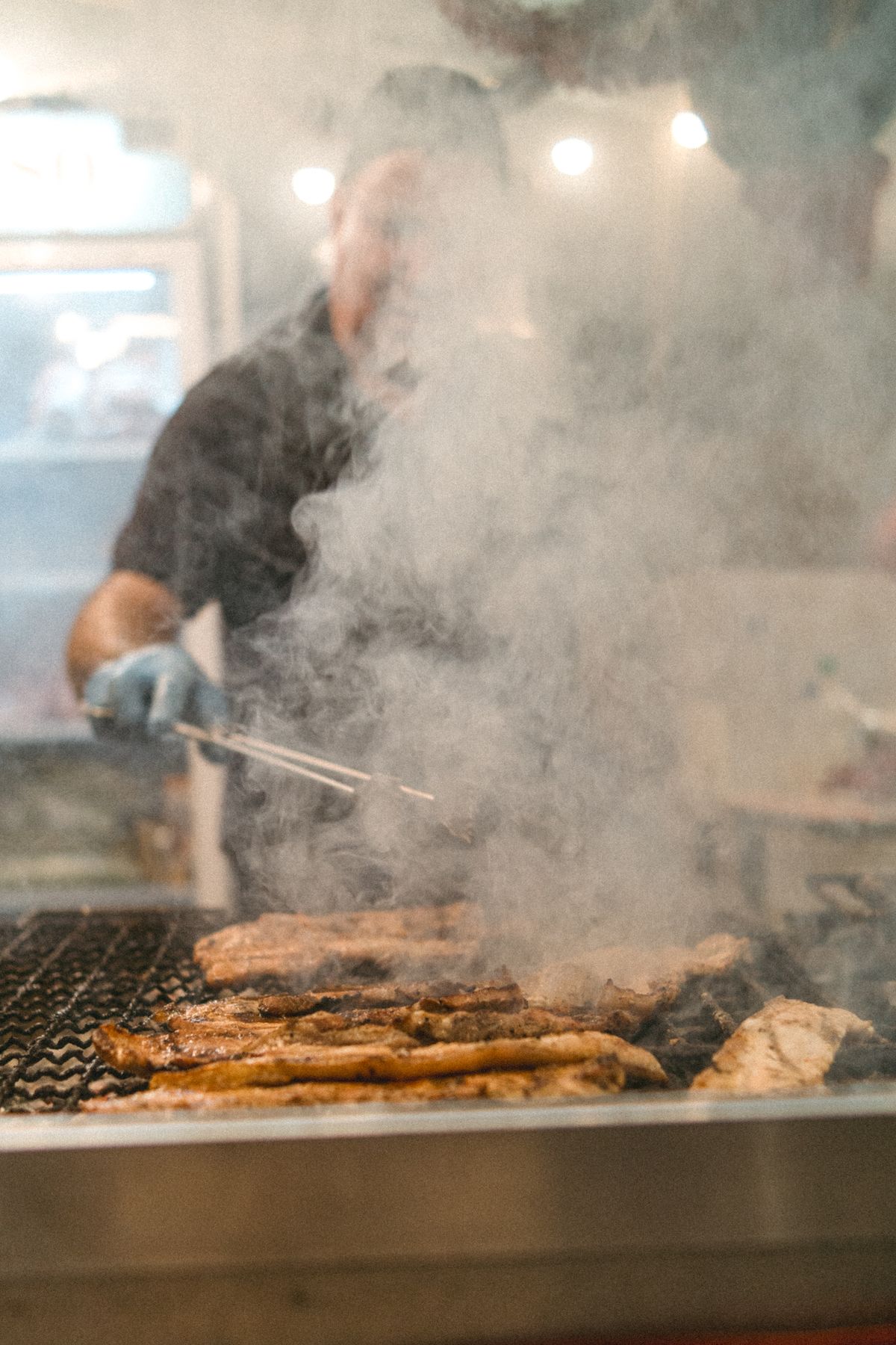 Pork tenderloin searing over hot grill grates with steam rising