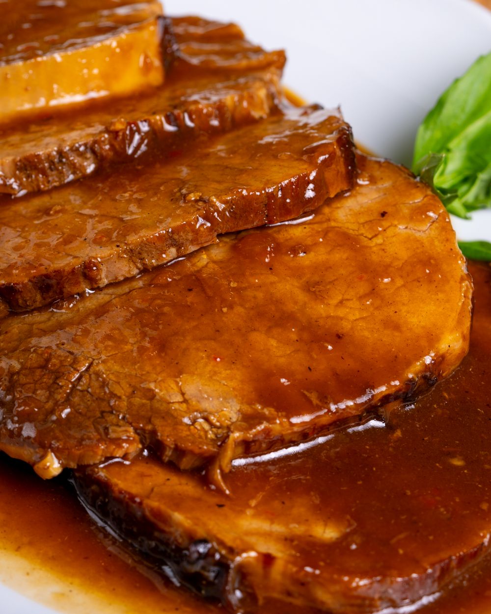 Sliced beef pot roast drenched in rich porcini and red wine gravy on a plate