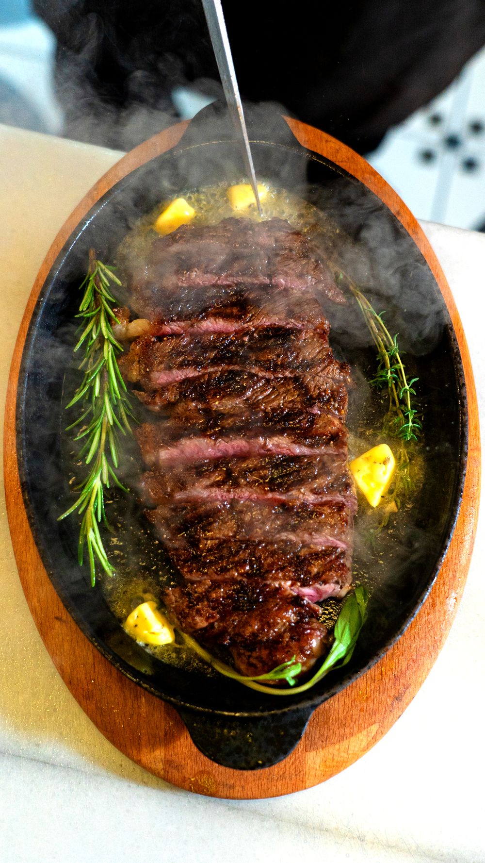 Rested bison steak with herb butter melting on top before slicing