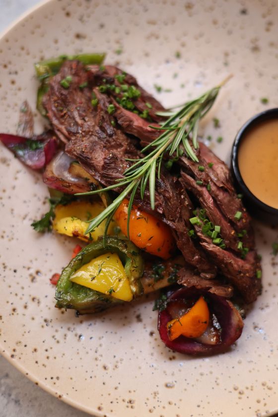 Garlic and herb roast leg of lamb resting on a platter with roasted vegetables