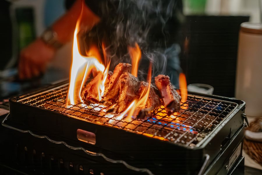 Beef short ribs cooking low and slow over smoke on a barbecue