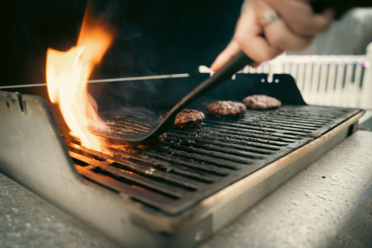 Bison burger patties searing on a hot grill grate