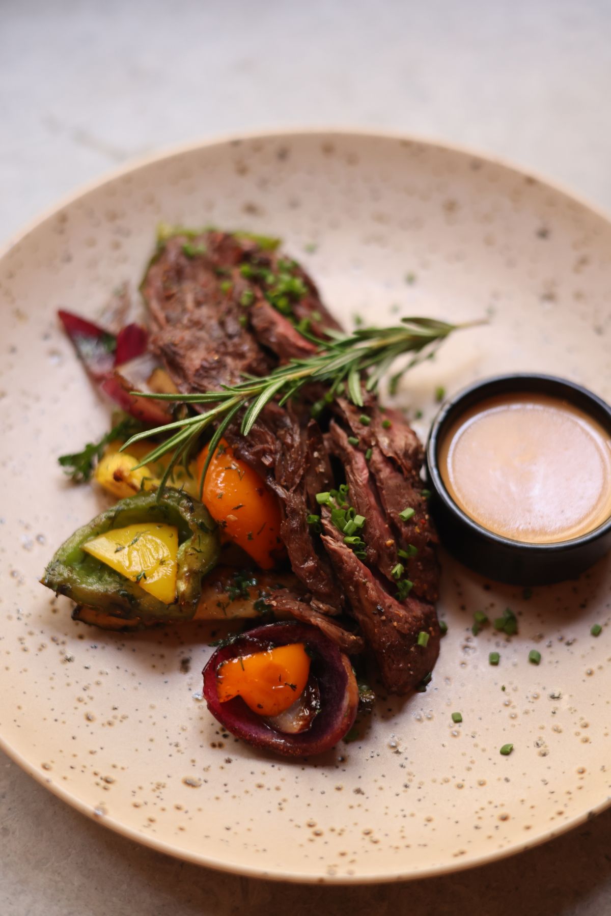 Sliced hanger steak with green chimichurri sauce and vegetables