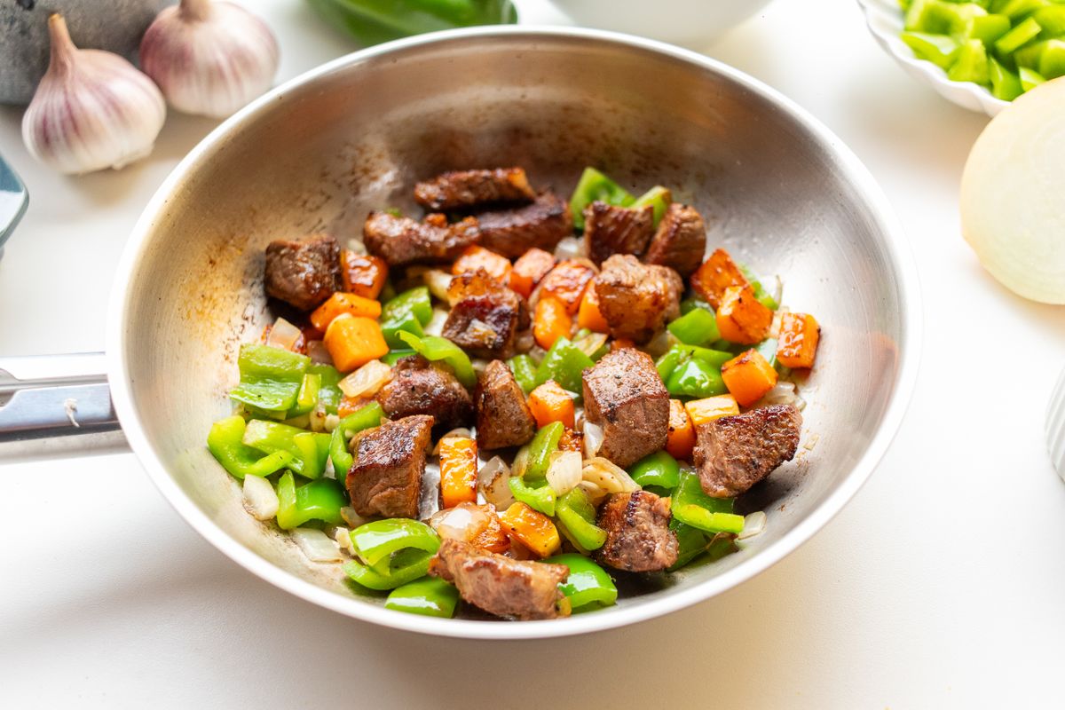 Sizzling hanger steak stir fry with vegetables in a hot pan
