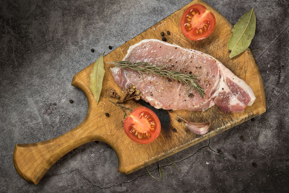 A pork chop searing in a hot cast iron pan