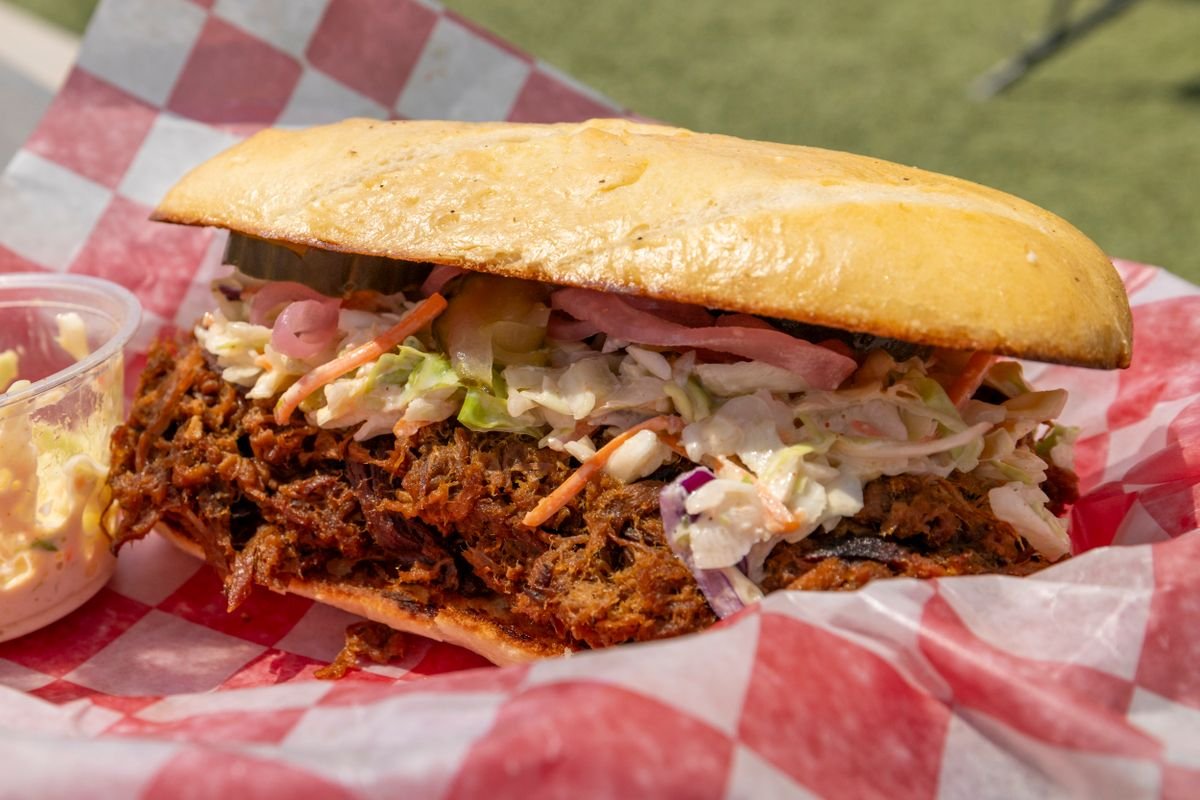 Pulled pork sandwich piled high with slaw on a soft bun