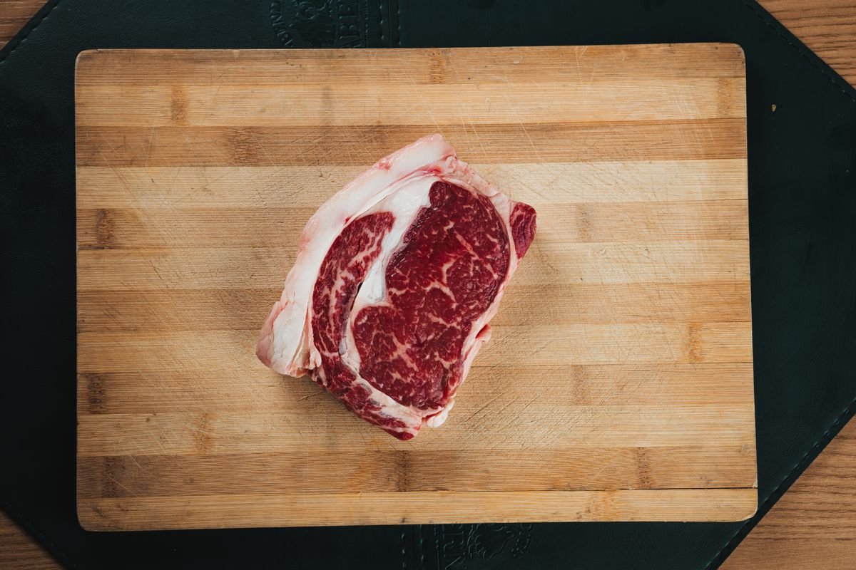 A well marbled raw ribeye steak on a cutting board