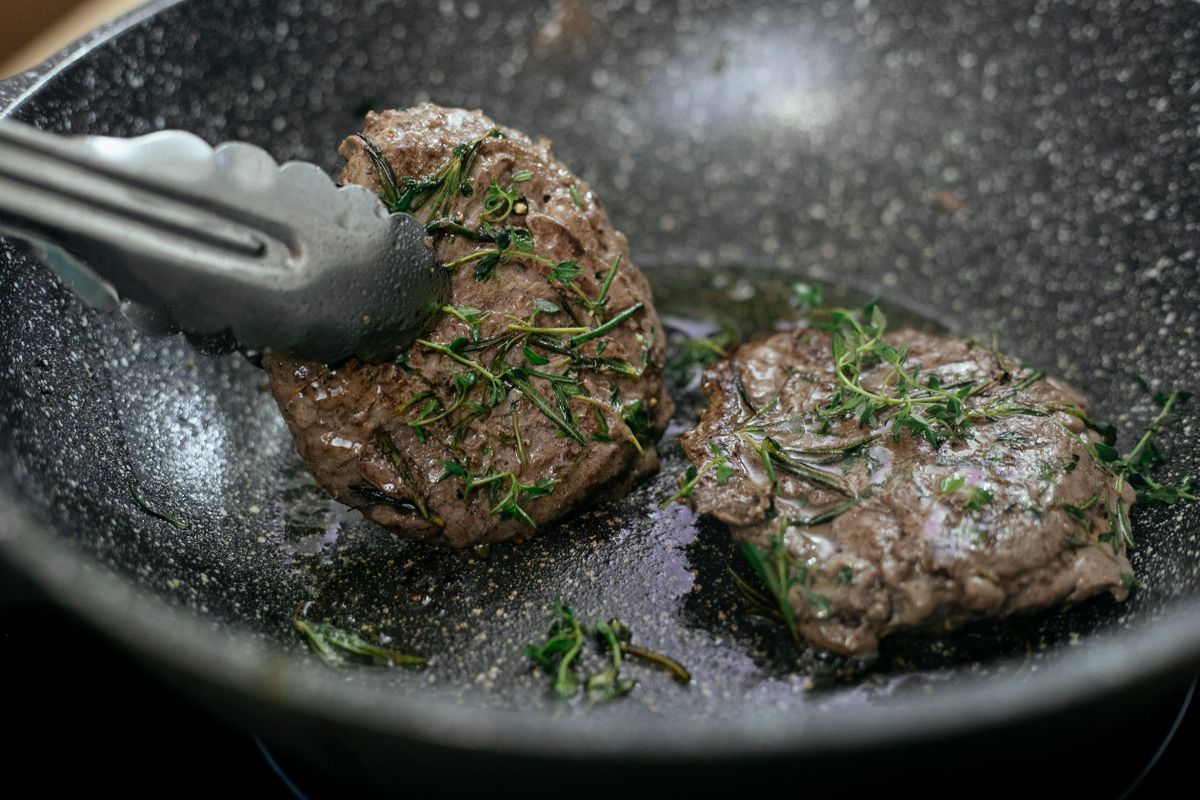 A steak searing and browning deeply in a hot pan