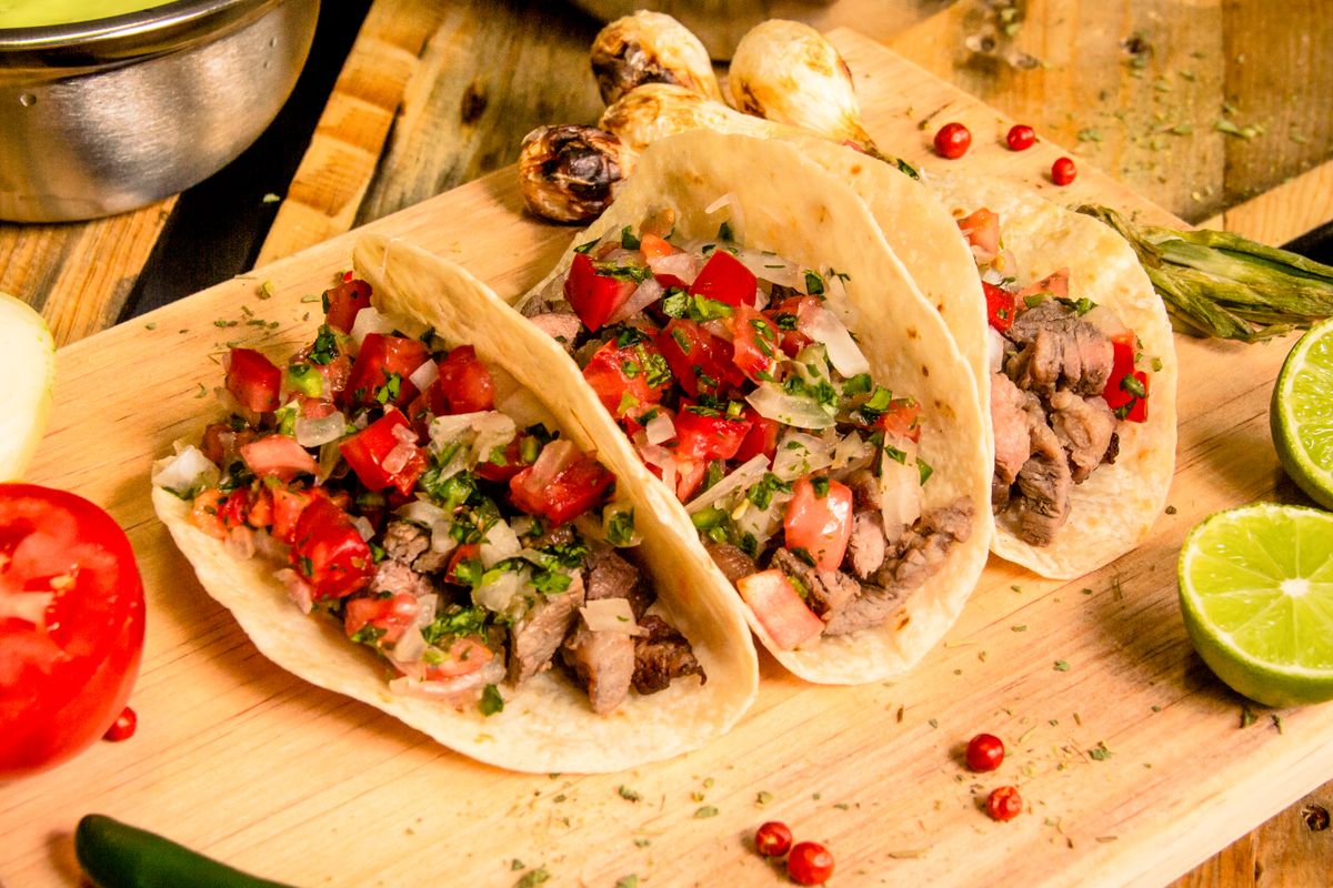 Steak tacos topped with diced onion and fresh cilantro