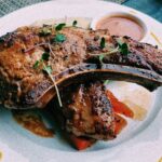 Seared bone-in veal chop with pan jus and fresh herbs on a white plate