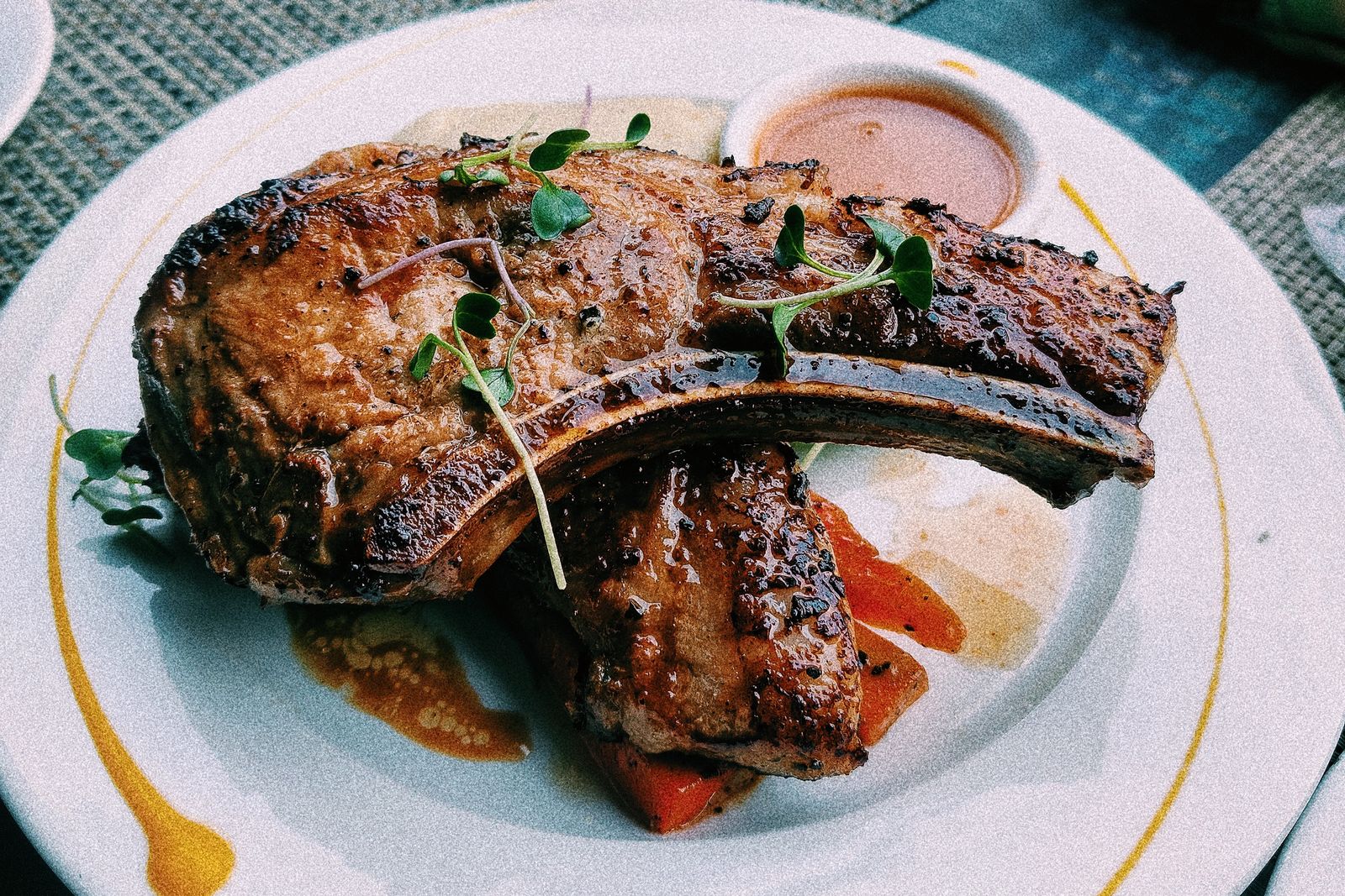 Seared bone-in veal chop with pan jus and fresh herbs on a white plate
