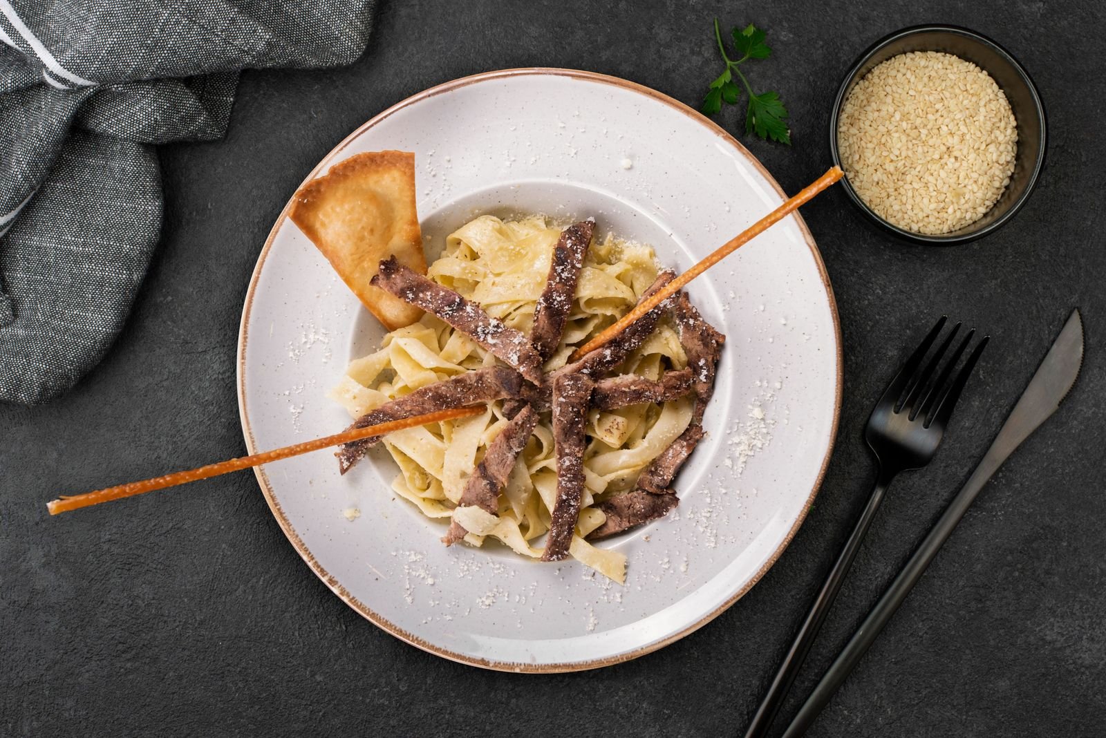 Strips of beef served over wide buttered egg noodles on a white plate, the classic way to plate stroganoff