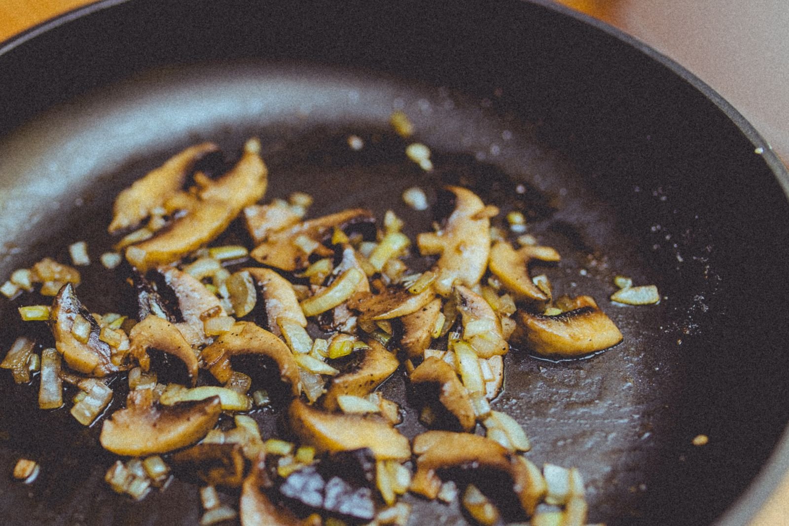 Sliced wild mushrooms and onions browning in a cast iron skillet for beef stroganoff sauce