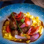 Beef stroganoff with wild mushrooms in a creamy pan sauce, served over egg noodles in a blue bowl