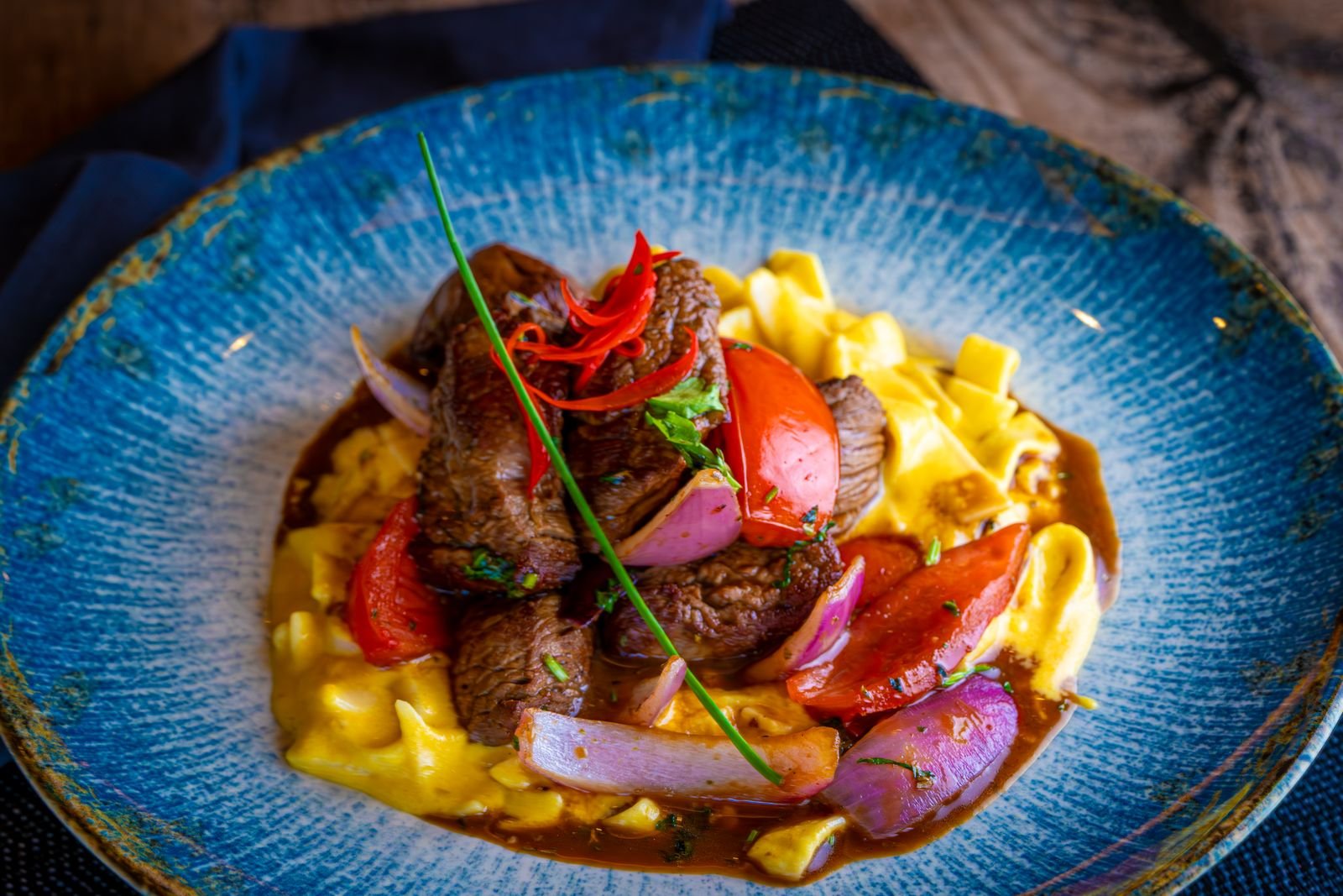 Beef stroganoff with wild mushrooms in a creamy pan sauce, served over egg noodles in a blue bowl