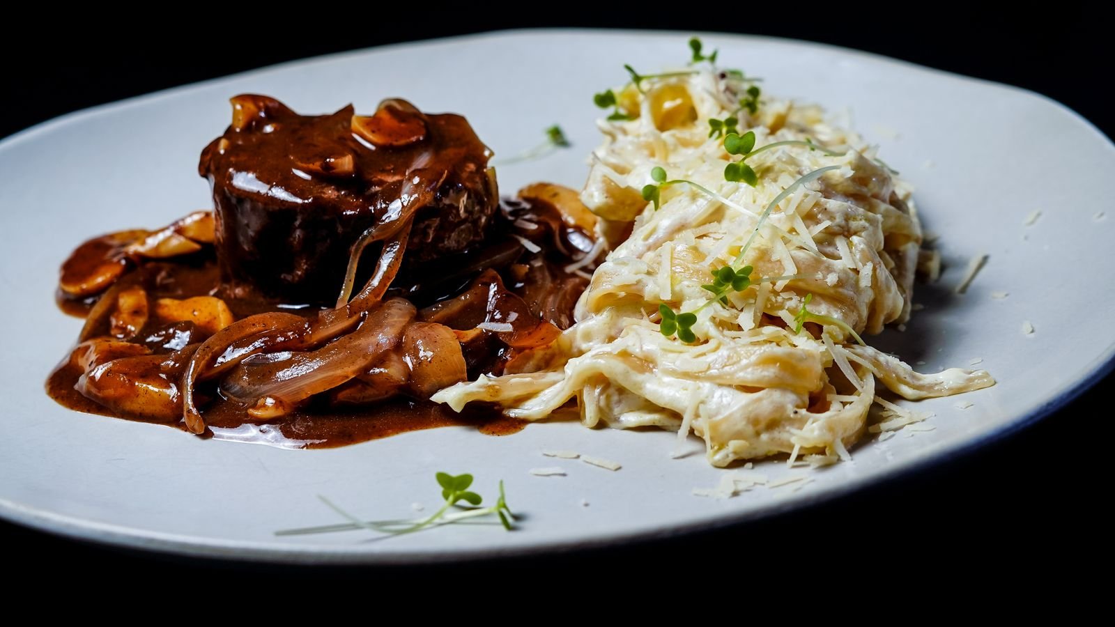 Braised meat in a glossy mushroom sauce spooned over noodles