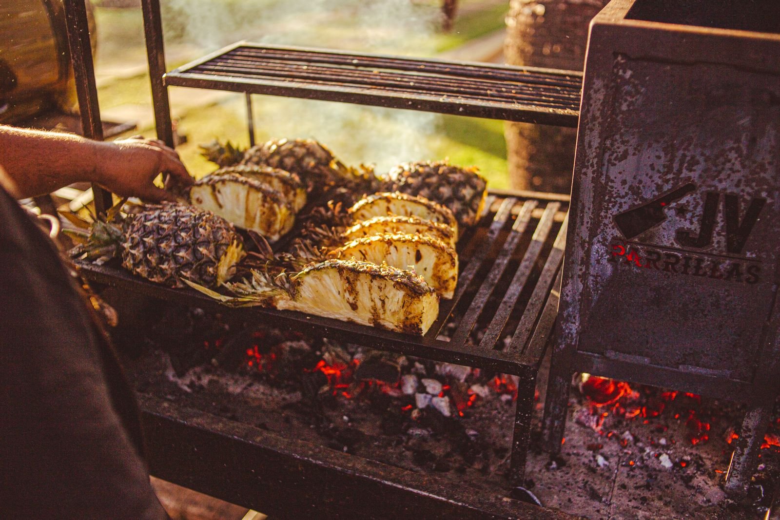 Pineapple slices charring on a hot charcoal grill for carnitas tacos