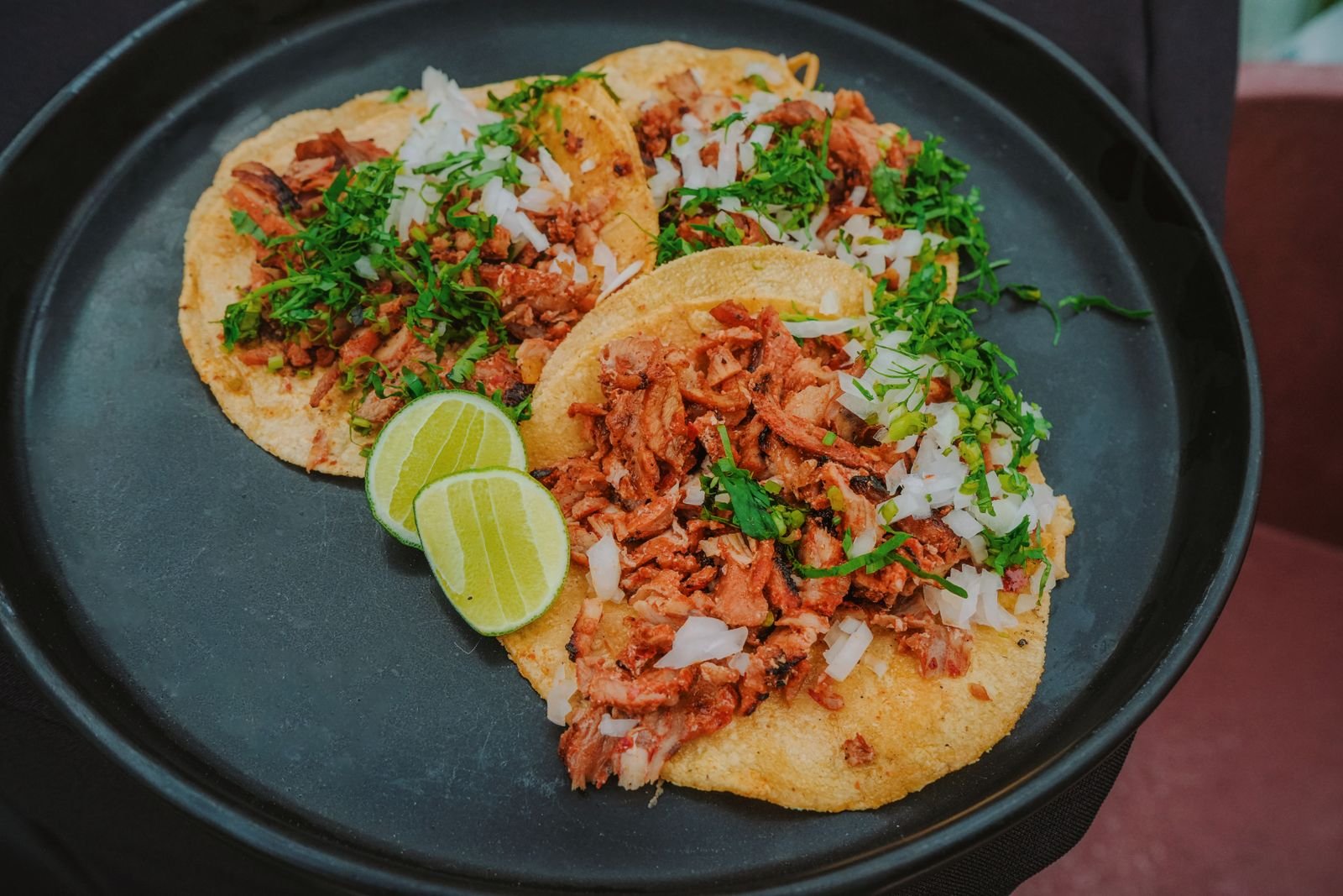 Pork tacos garnished with cilantro, onion and lime on corn tortillas