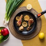 Cast iron chicken thighs with charred lemon slices and capers in a skillet