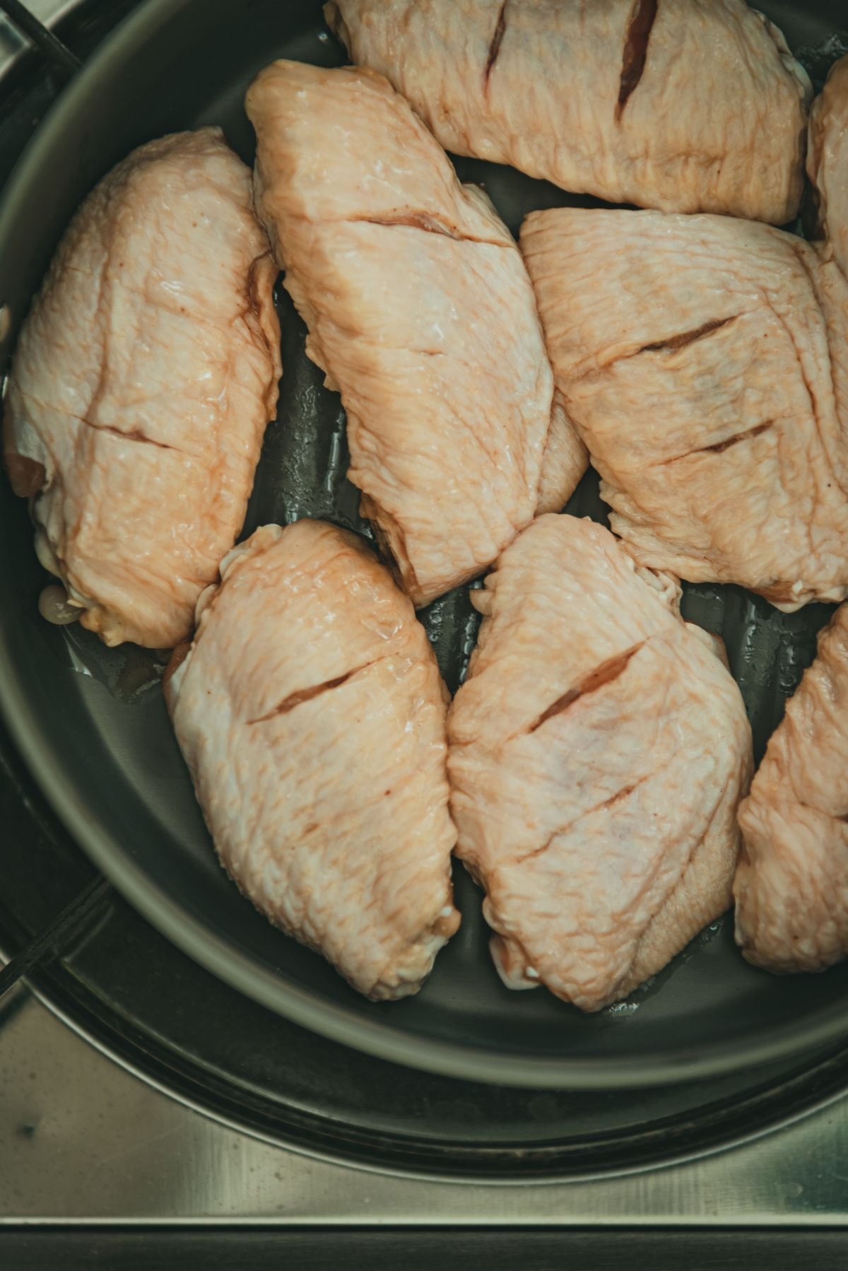 Bone-in skin-on chicken thighs dried and salted in a pan before searing
