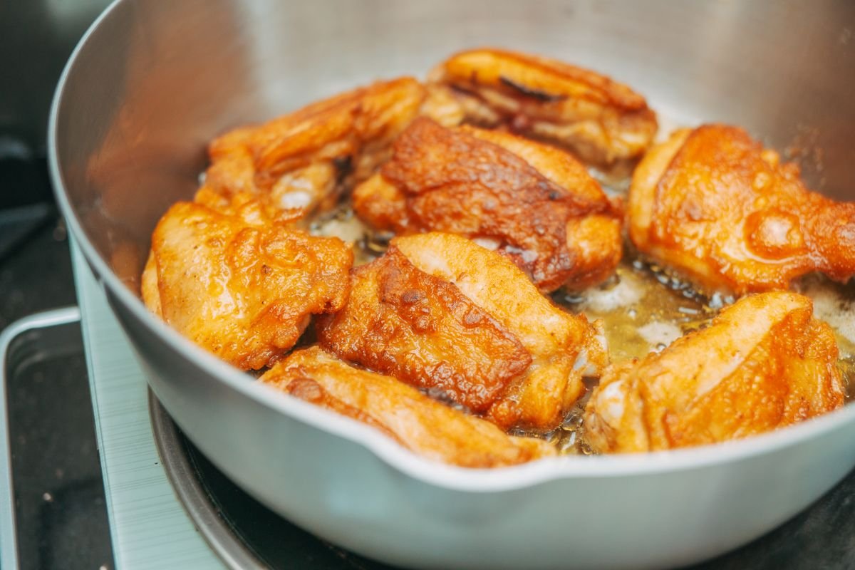Chicken thighs searing skin side down in a cast iron skillet until golden and crisp