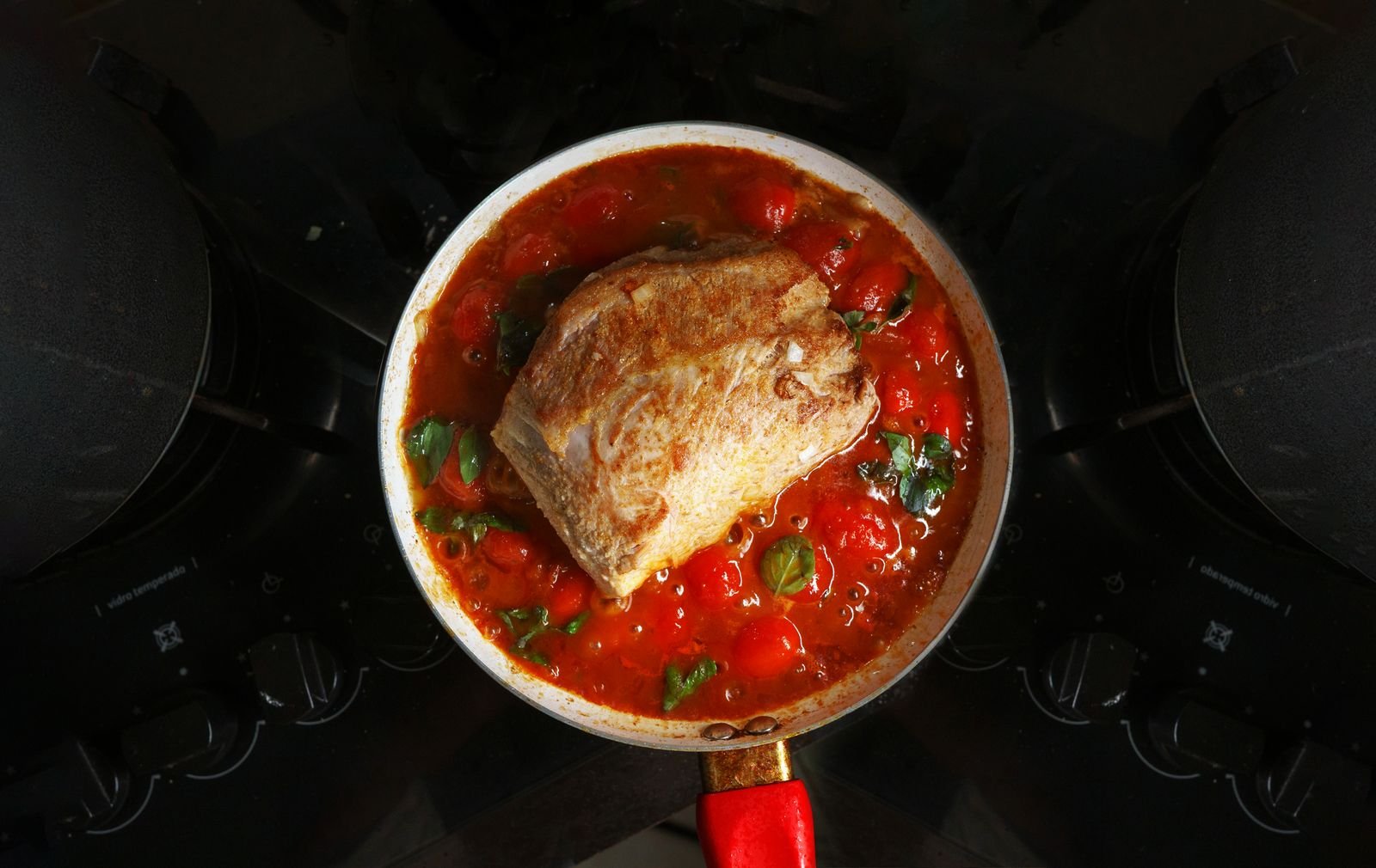 Beef chuck braising in a heavy pot with herbs and dark sauce