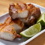 Cuban mojo pork with crisp skin and lime wedges ready to be pulled apart