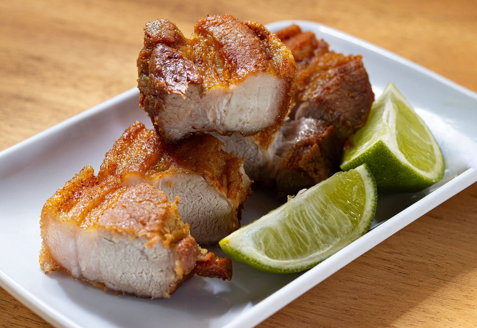 Cuban mojo pork with crisp skin and lime wedges ready to be pulled apart