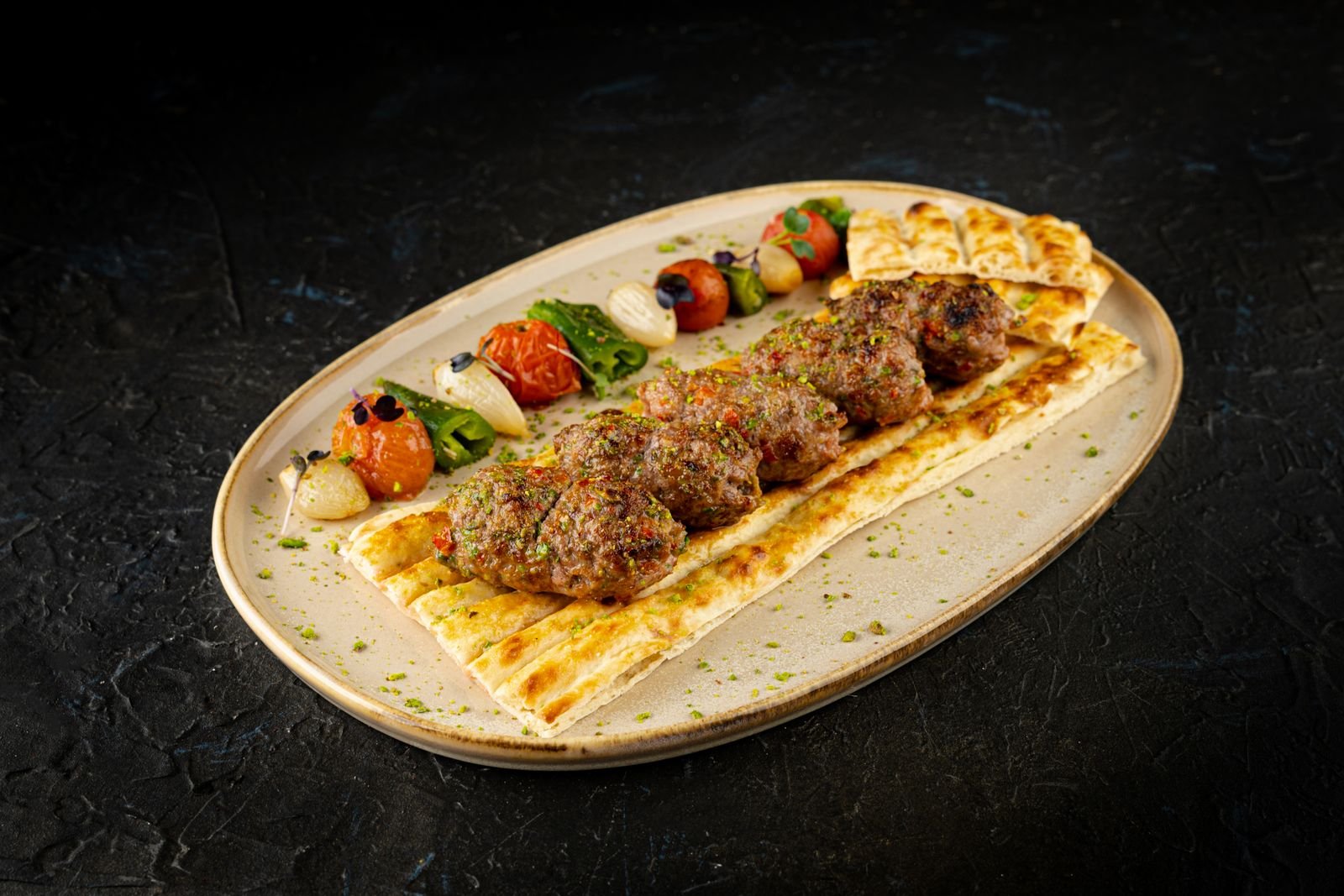 Grilled lamb kofta on flatbread with charred vegetables and herbed yogurt