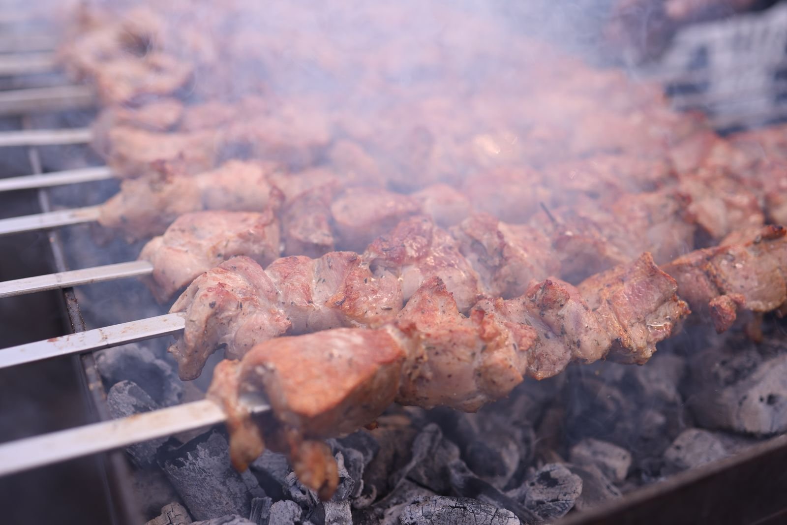 Cubed lamb skewers turning over charcoal with charred edges