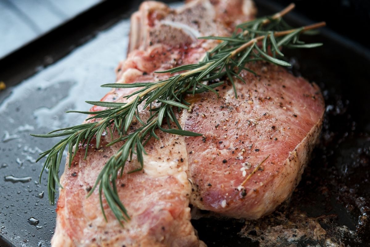 Thick cut pork chop searing in a hot cast iron skillet