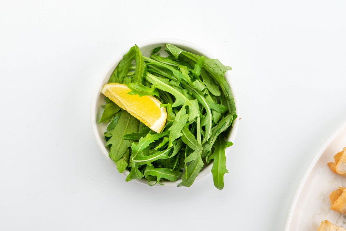 Fresh arugula with a lemon wedge in a bowl for the veal Milanese salad topping