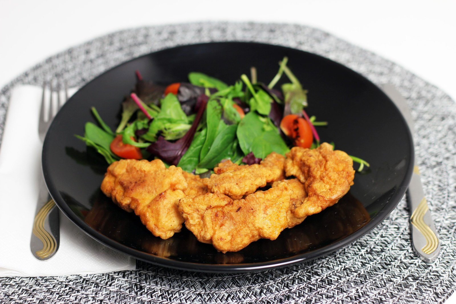 Veal Milanese cutlet on a dark plate with a marinated mushroom and arugula salad