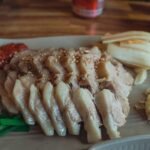 Sliced Korean bossam pork arranged on a platter with kimchi and garlic
