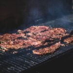 Skirt steak for carne asada searing over a hot grill with smoke rising