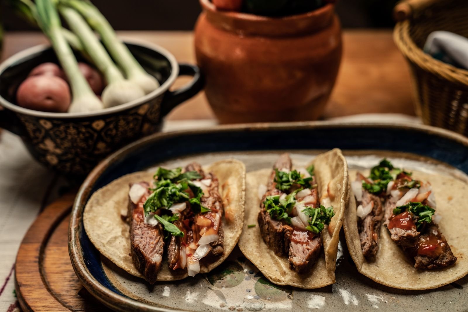 Carne asada steak tacos topped with cilantro and onion on corn tortillas