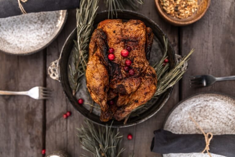 Whole roasted turkey with deep brown skin garnished with cranberries on a wooden table, seen from above