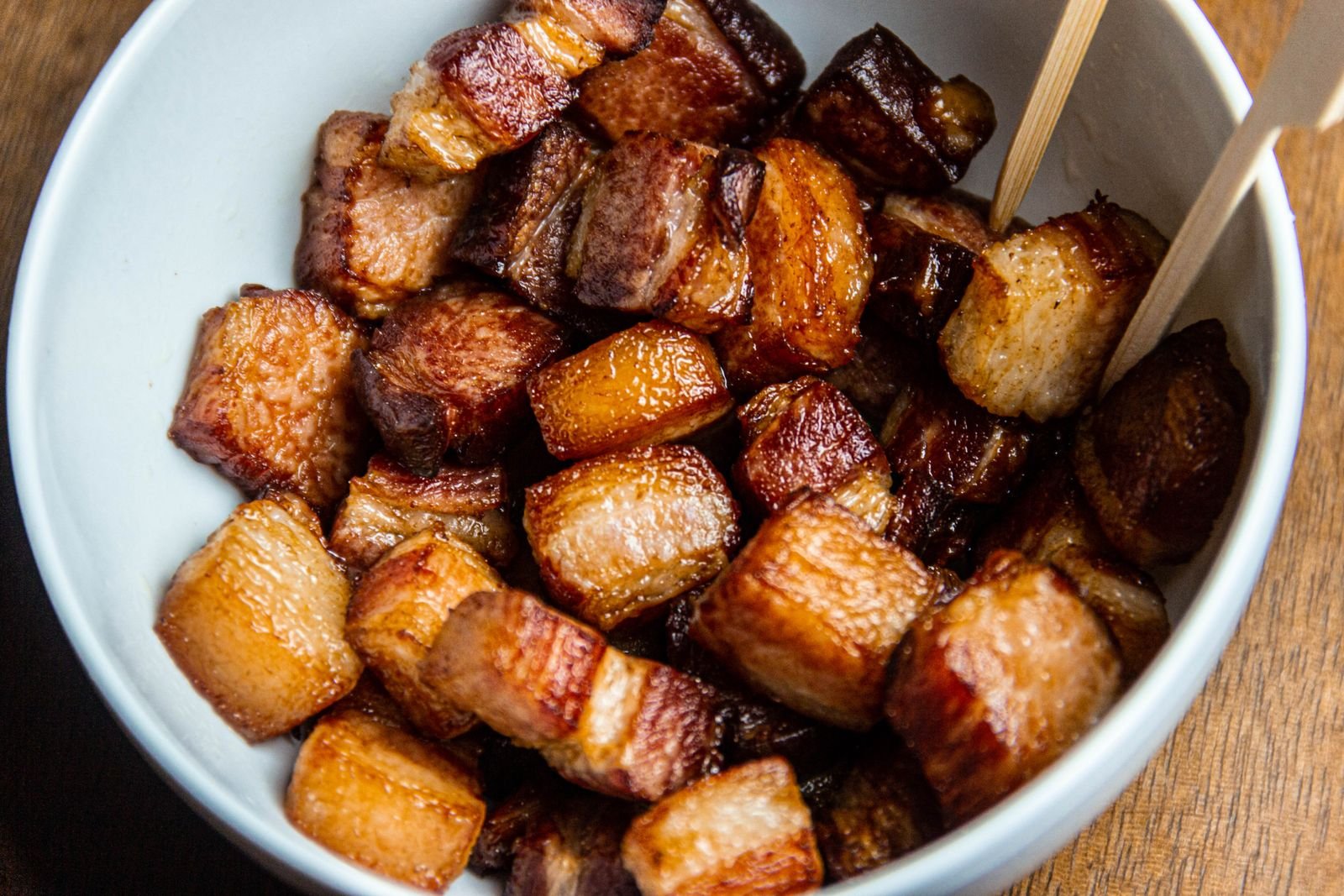 Crisp glazed pork belly burnt end cubes served in a white bowl