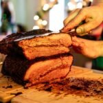 Smoked brisket sliced on a wooden board showing dark bark and a pink smoke ring