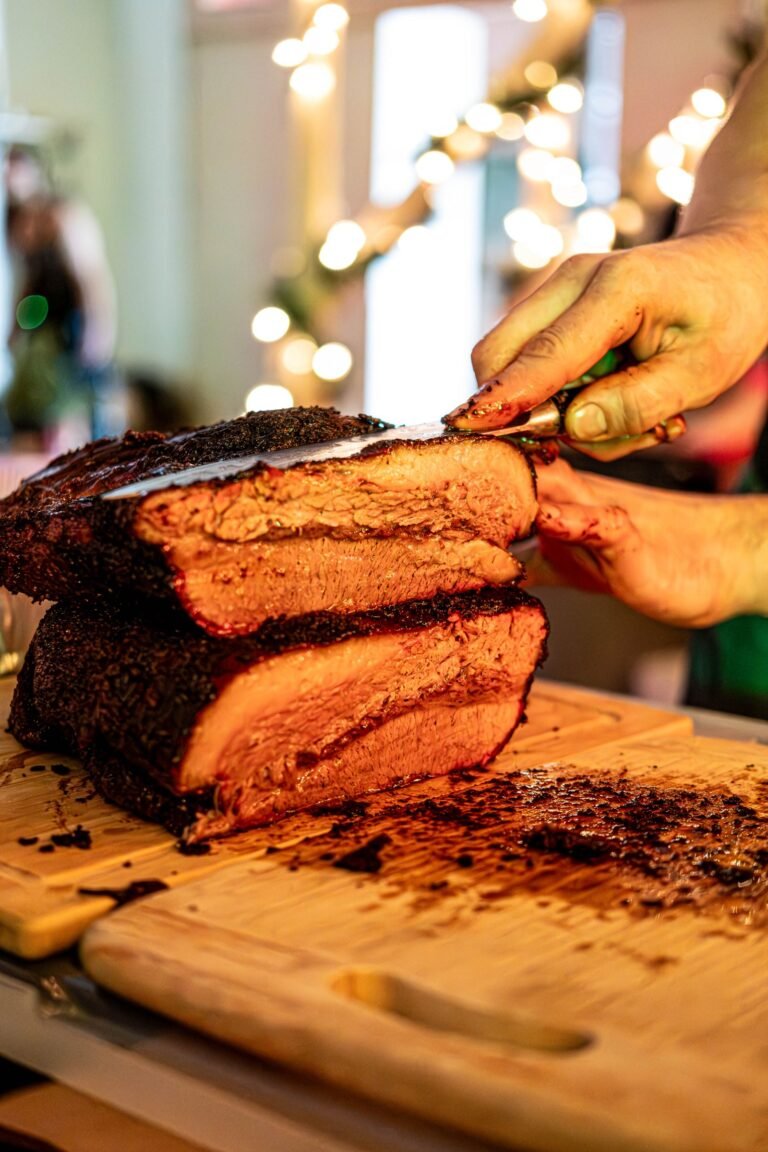 Smoked brisket sliced on a wooden board showing dark bark and a pink smoke ring
