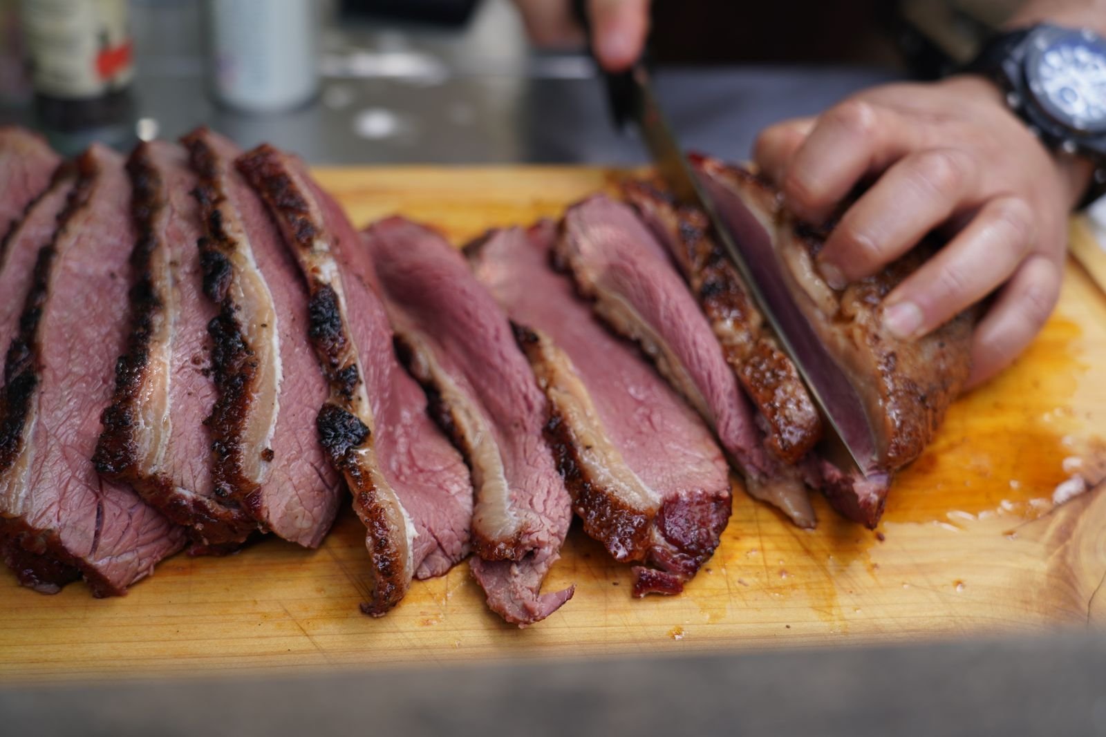 Slicing juicy smoked beef brisket against the grain on a wooden cutting board