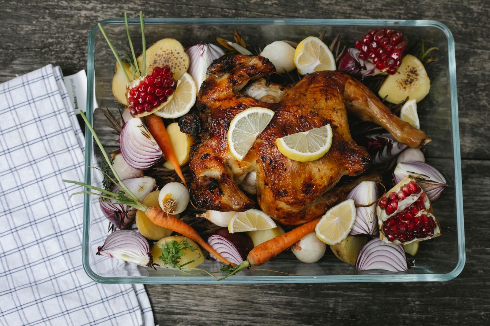 Roast chicken with lemon slices and onion in a baking dish